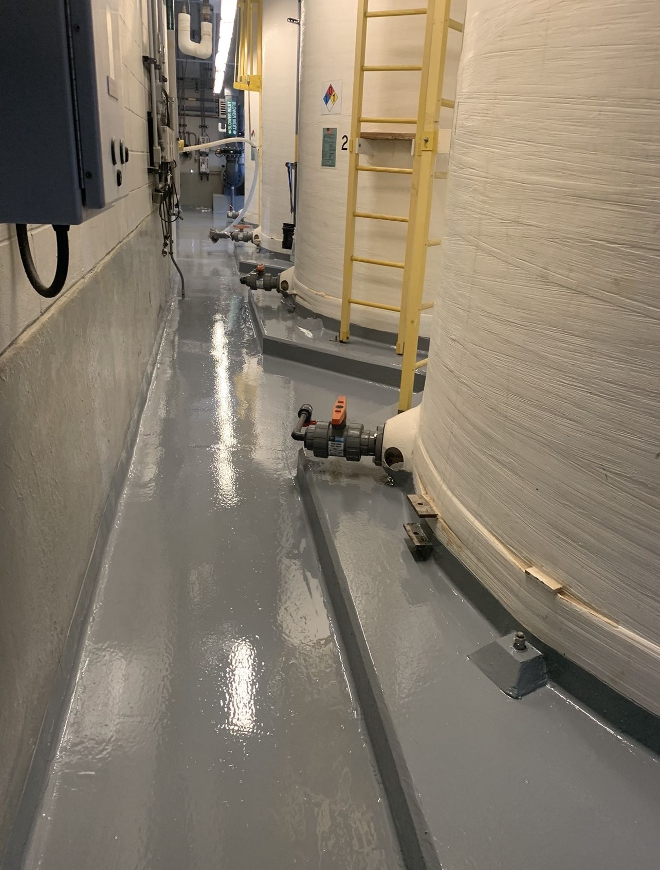 Chemical containment area finished with a continuous grey protective coating over floor and curbs